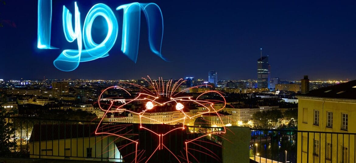 Vue nocturne de Lyon avec des light-paintings représentant le mot 'Lyon' et une tête de lion, depuis un point panoramique