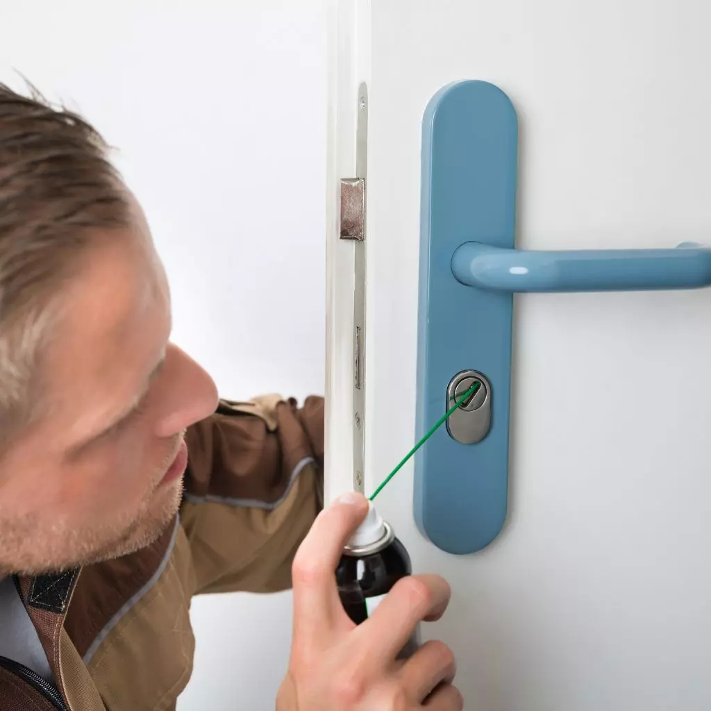 Serrurier Villeurbanne 2 Un serrurier applique un spray lubrifiant dans une serrure pour assurer un fonctionnement fluide et prolonger sa durabilité.