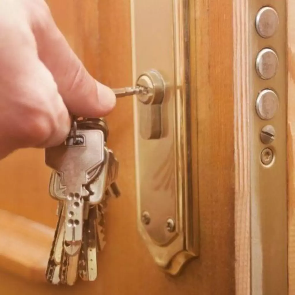 Serrurier Lyon 19 Main insérant une clé dans une serrure multipoints sur une porte en bois, garantissant une sécurité renforcée