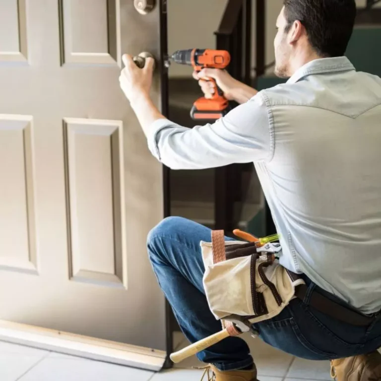 Serrurier effectuant l'installation d'une serrure sur une porte d'entrée avec une perceuse et un équipement professionnel.