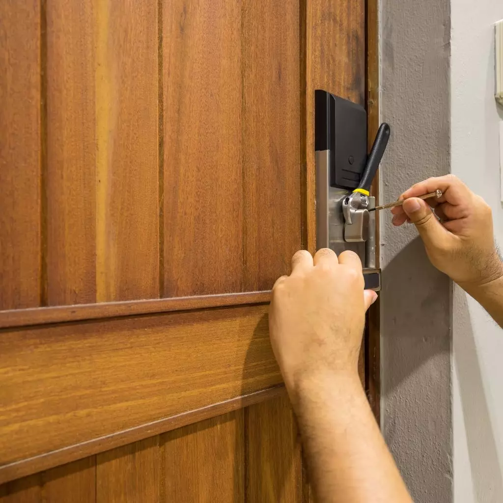 Serrurier Lyon 5 2 Serrurier manipulant une serrure électronique sur une porte en bois pour une ouverture ou un dépannage