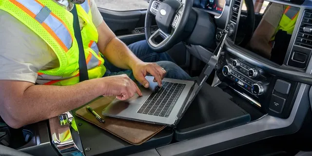 Technicien utilisant un ordinateur pour programmer une clé de voiture dans l’habitacle
