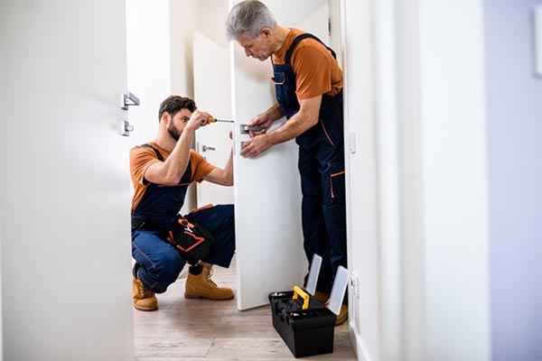 Photo : deux serruriers travaillant ensemble sur une serrure de porte à Saint-Fons.