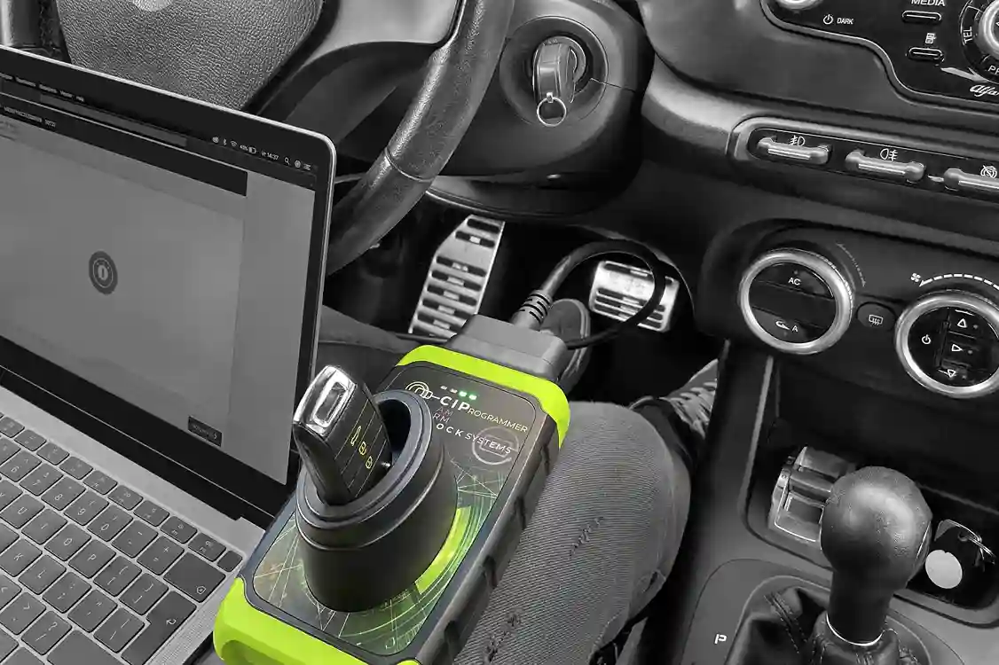 Serrurier Oullins effectuant la programmation et la reprogrammation de clé de voiture avec un appareil électronique professionnel à l’intérieur d’un véhicule.